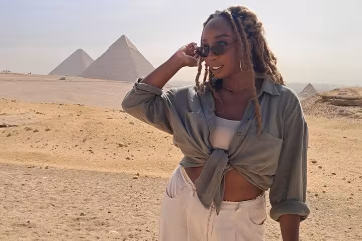 Woman in sunglasses at Giza Plateau with pyramids backdrop, part of Grand Egyptian Museum tour and lunch
