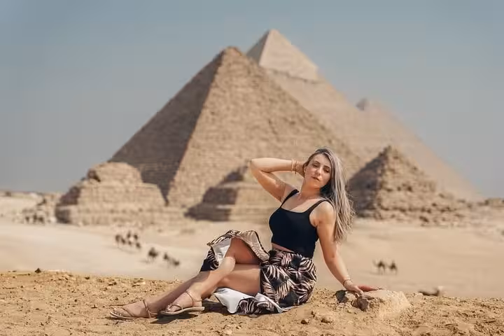 Woman posing in the desert with the Great Pyramid of Giza behind on a full-day Giza, Sakkara and Memphis tour