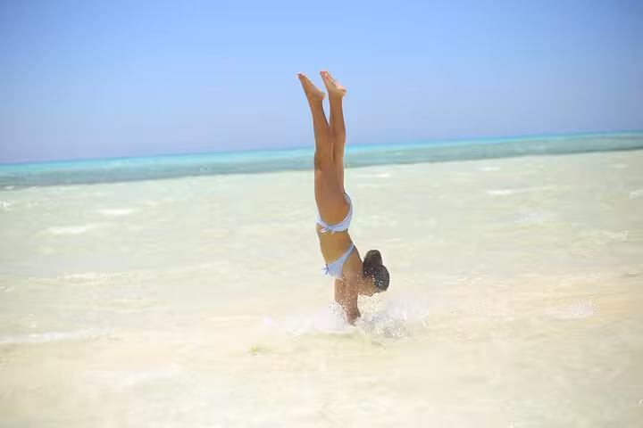 Woman doing a handstand in shallow turquoise water at White Island on Sharm El Sheikh day sail excursion