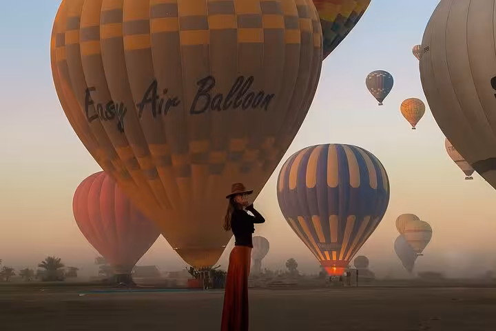 Woman standing by Easy Air Balloon at sunrise in Luxor, Egypt, before hot air balloon flight with transfer