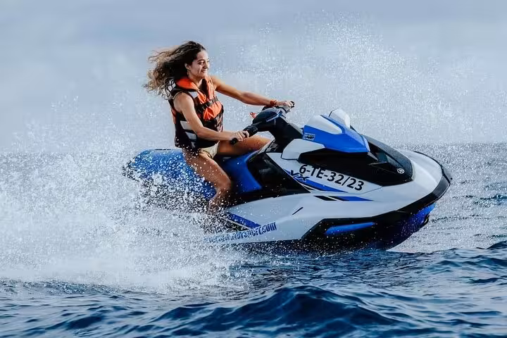 Woman riding a jet ski in Dubai, splashing across the Arabian Gulf on a 30-minute or 1-hour tour
