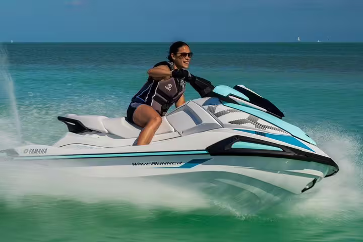 Woman driving a jet ski tour from San Antonio Ibiza to Margaritas Islands, carving through clear water