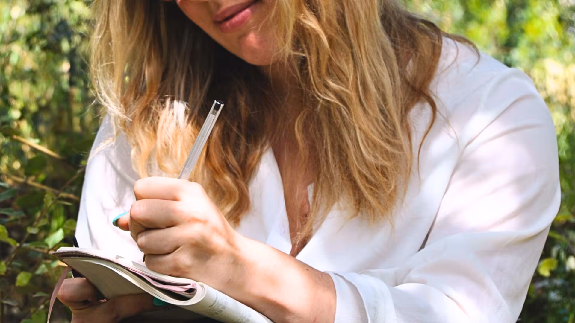 Woman journaling in serene forest setting during Perfugas Green Mindfulness experience.