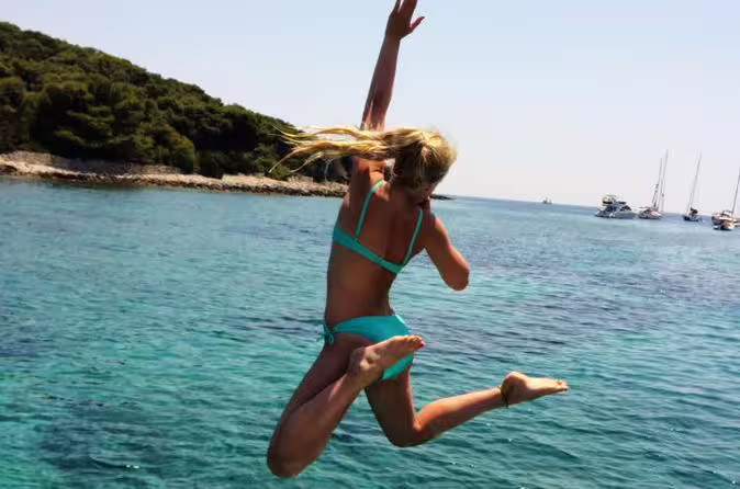 Woman jumps into crystal-clear Blue Lagoon on private boat tour to Šolta islands near Split, Croatia