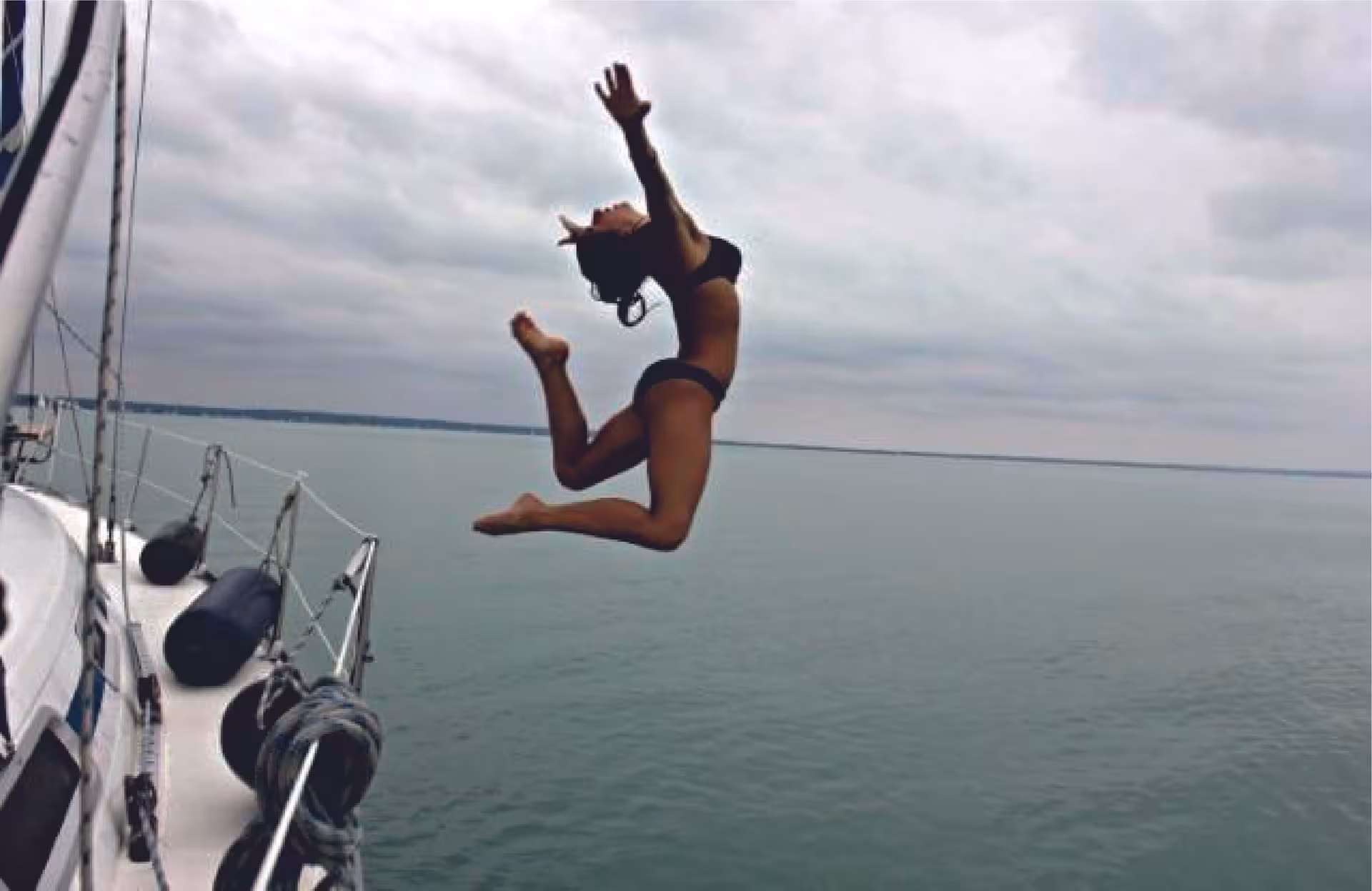 Woman jumping off a sailboat into calm sea during Fun & Swim tour, ocean swim and boat adventure