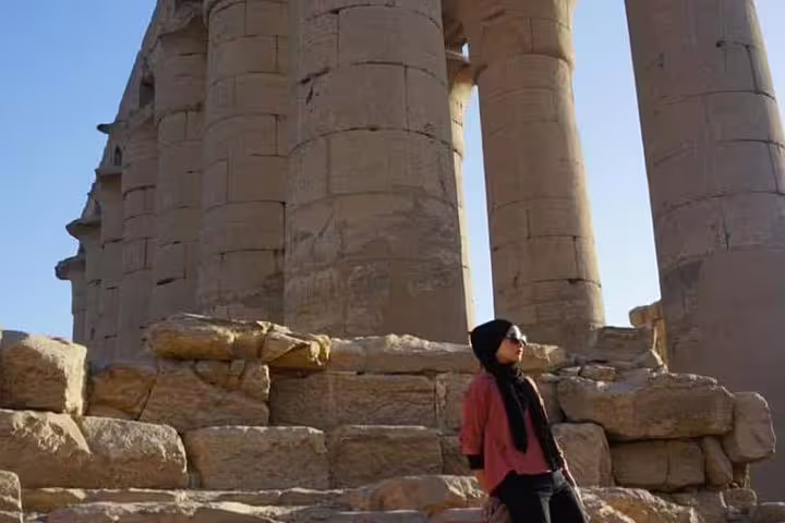 Woman at Karnak Temple columns in Luxor, Egypt spiritual tour visiting ancient ruins, meditation and history