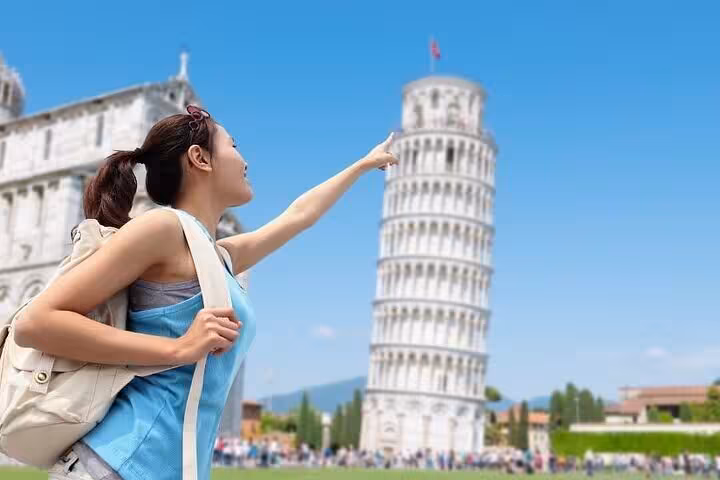 Woman pointing at the Leaning Tower of Pisa during a sunny day on the Discover Lucca and Pisa tour.