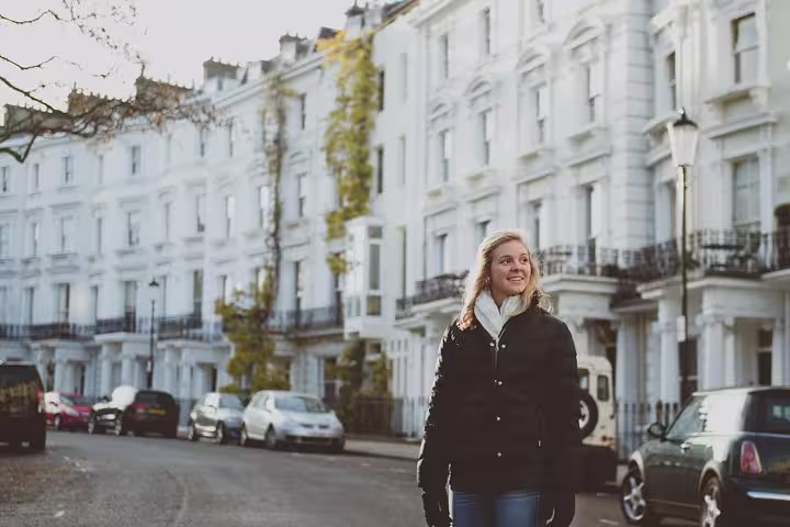 Smiling woman strolls down a picturesque London street with elegant white townhouses lining the background.