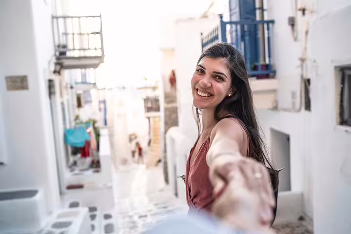Smiling woman in Mykonos Little Venice alley during private photoshoot, guided by professional photographer