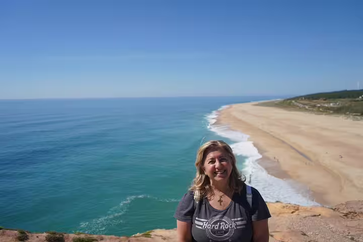 Woman enjoying stunning ocean view at Nazaré beach, a highlight of the Óbidos, Alcobaça, and Fátima full-day tour from Lisbon.