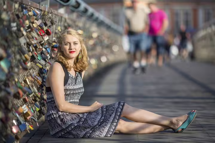Woman in summer dress sitting on Paris bridge with love locks, enjoying the Highlights & Secrets of Paris Private Tour.