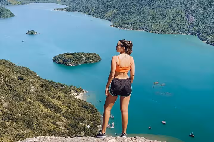 Woman in sportswear enjoys breathtaking view from Peak Sugar Bread, overlooking lush islands and azure waters.