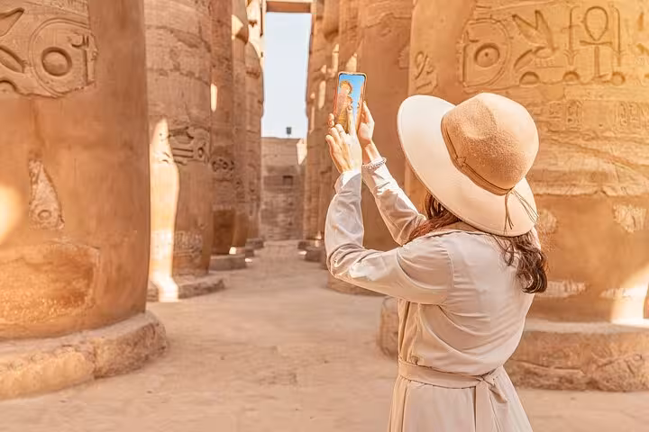 Woman photographing Karnak Temple hieroglyphs in Luxor during 2-day private tour from Hurghada