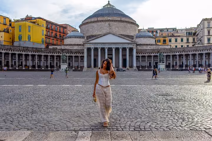 Woman posing in front of the historic Piazza del Plebiscito in Naples, surrounded by neoclassical architecture.