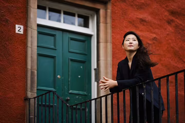Portrait of woman by teal door on red wall in Edinburgh, captured on a private photoshoot with pro photographer