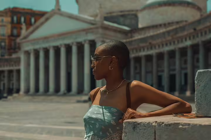 Woman in stylish attire poses in front of historic architecture during a Naples photoshoot with a professional photographer.