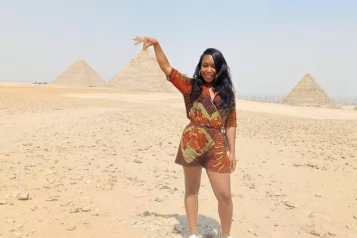 Woman posing with Pyramids of Giza in background on Cairo private tour to Giza and Saqqara with Egyptian lunch