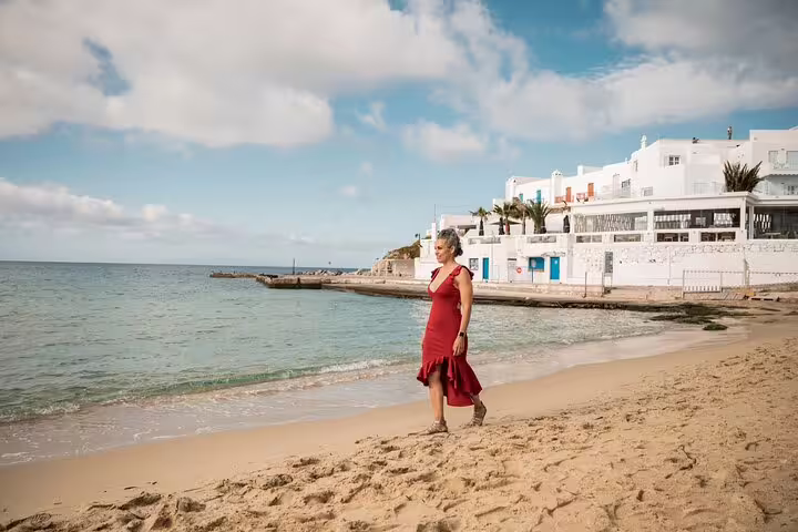 Woman in red dress walking Mykonos beach near Little Venice, private photoshoot with professional photographer