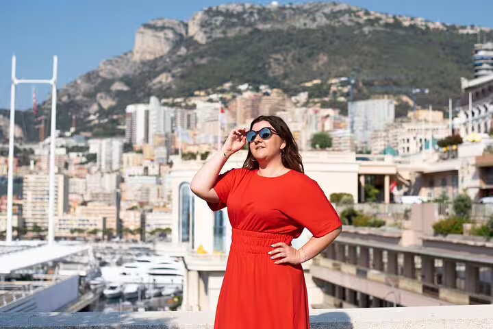 Woman in a red dress posing with sunglasses overlooking the scenic cityscape of Nice on a personal photography tour.