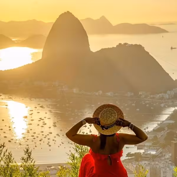 Woman in red dress enjoys stunning sunrise view of Sugarloaf Mountain from Dona Marta Viewpoint tour.