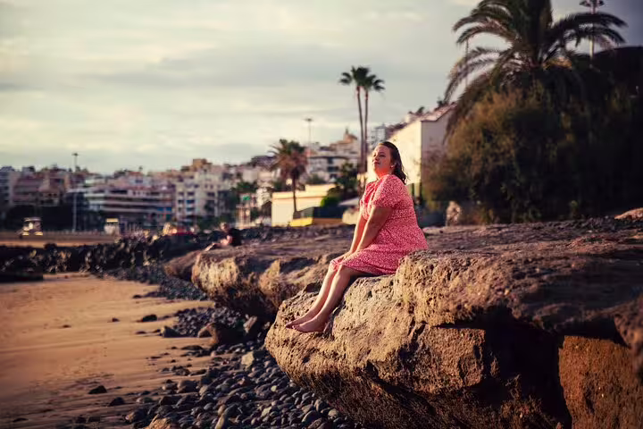Woman in red dress posing on coastal rocks in Tenerife for private photoshoot with a professional photographer