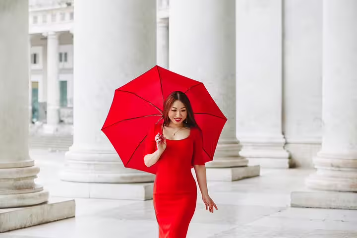 Woman in a red dress with a matching umbrella walking through the historic architecture of Naples.