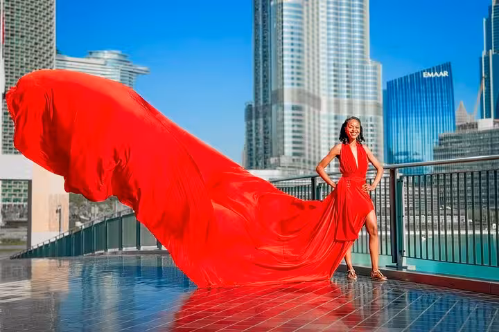 Woman in flowing red dress poses with Burj Khalifa backdrop for Instagram videography shoot in Dubai.