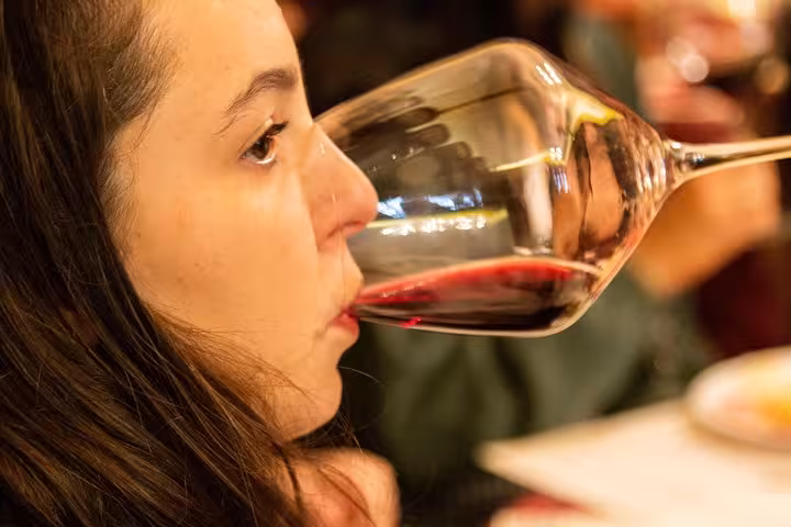 Close-up of a woman savoring a glass of red wine on a Tuscany wine tasting tour.