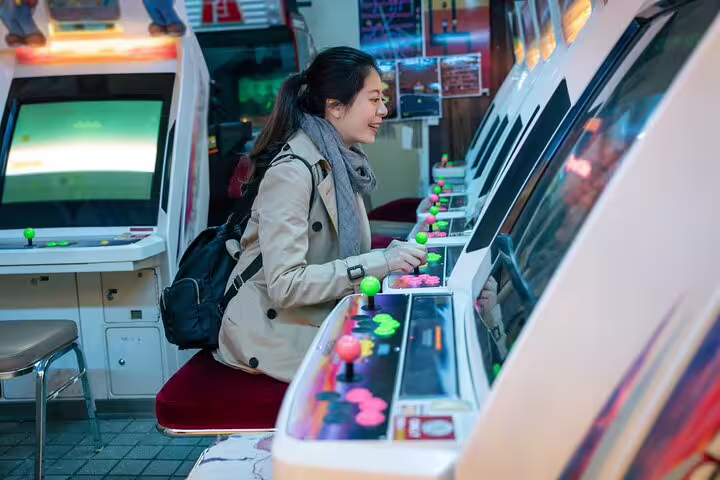 Woman enjoying retro arcade gaming in Osaka during personalized photoshoot session.