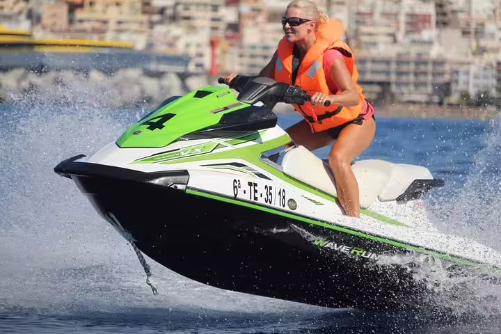 Woman in a life jacket riding a green jet ski, capturing the thrill of a 2-hour jet ski safari adventure.