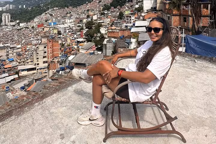 Woman relaxing on a rooftop in Rocinha favela with panoramic views of the sprawling urban landscape in Brazil.