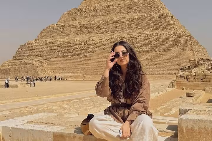 Woman sitting near Saqqara Step Pyramid ruins on a Giza Pyramids Saqqara Memphis day tour from Cairo