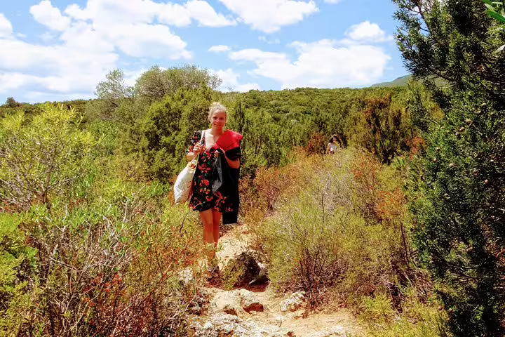 Woman walking through lush Arrábida Natural Park, enjoying a sunny day with snorkeling gear for the Arrábida Snorkeling & Wine tour.