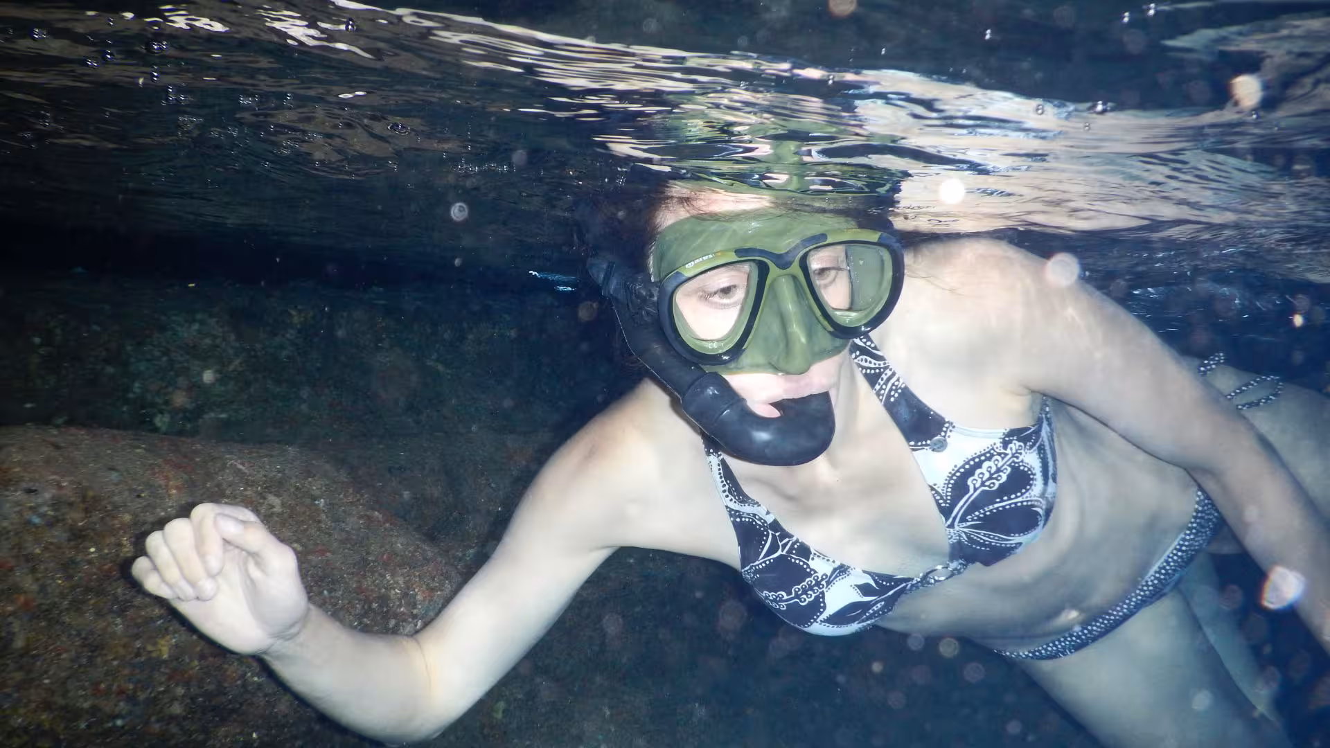 Woman snorkeling near rocks in the Orosei Gulf's clear waters, enjoying an aquatic adventure from Cala Gonone.