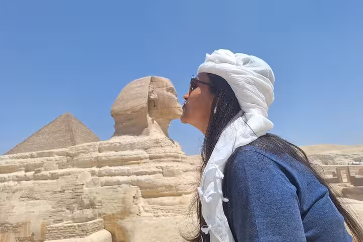Woman posing creatively with the Sphinx in Giza, highlighting the unique experiences of an Egypt tour with Nile cruise.
