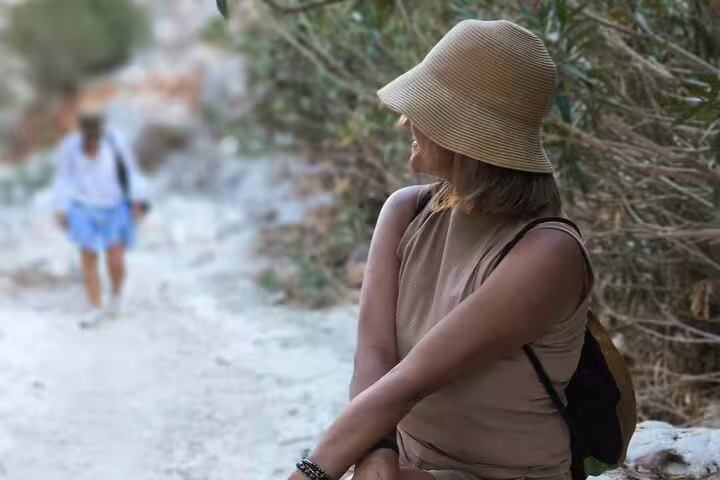 Woman in a sun hat enjoying a scenic walk near Seitan Limania beach, surrounded by lush greenery.