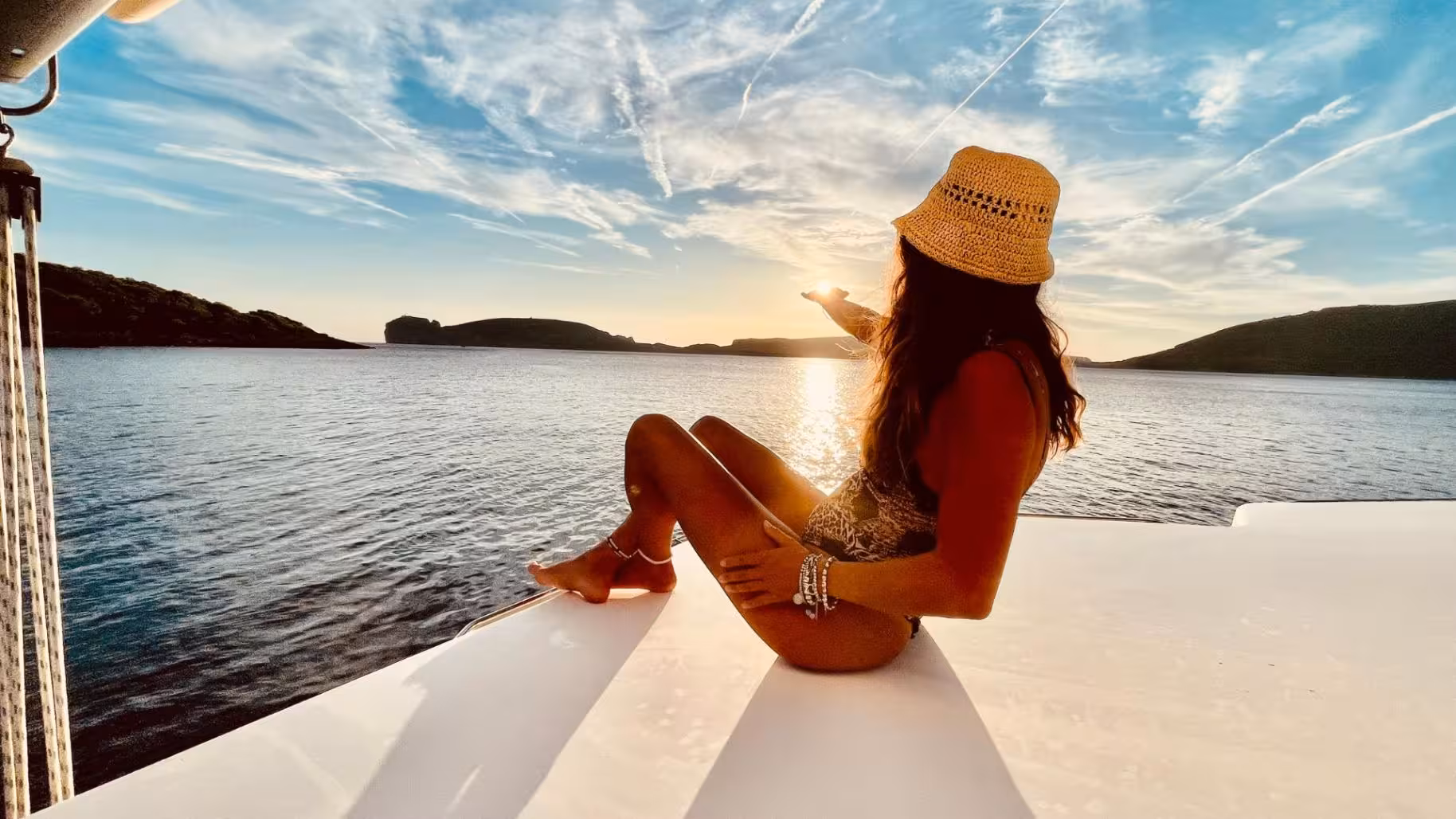 Woman enjoying sunset on a catamaran in Porto Conte Park, Alghero.