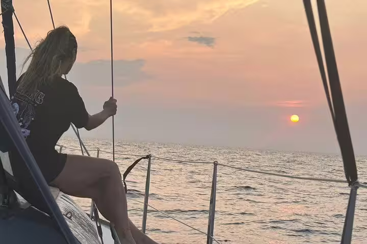 Woman enjoying a stunning sunset on a sailboat during a private day trip to Ibiza and Formentera, with serene ocean views.