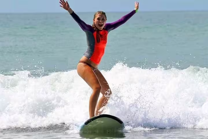 Excited woman successfully riding a wave during surf lessons in Manuel Antonio.
