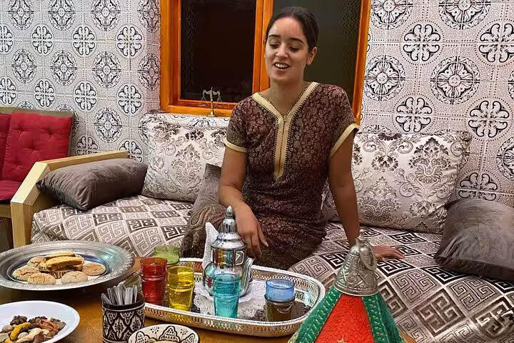 Woman enjoying traditional tea and snacks in a cozy room during a cultural cooking class experience.