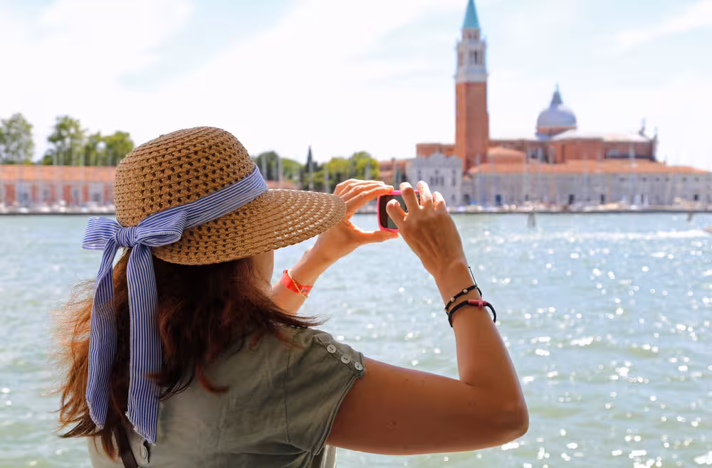 Woman in sunhat taking photo of Venice's iconic landmarks during a guided promenade tour.