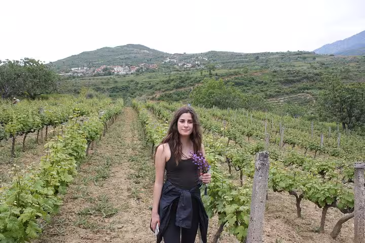 Woman holding flowers in a lush vineyard during the Grand Wine Tasting & Food Tour of Berat.