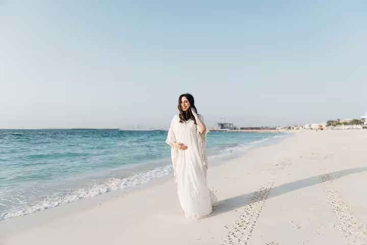 Woman in white dress walking on Dubai beach at sunrise, private personal travel photographer tour shoot
