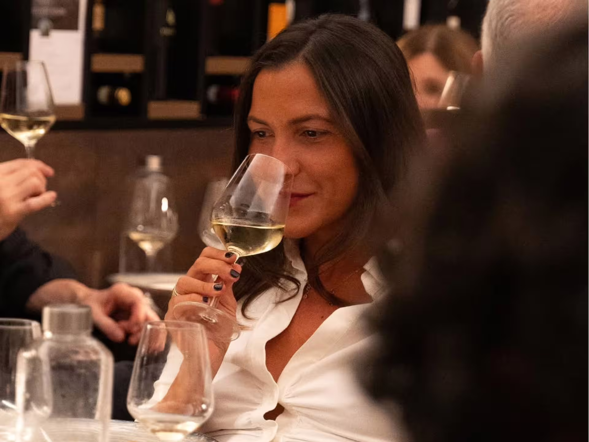 Woman smelling a glass of white wine during a luxury Modena city center wine tasting experience in an elegant enoteca