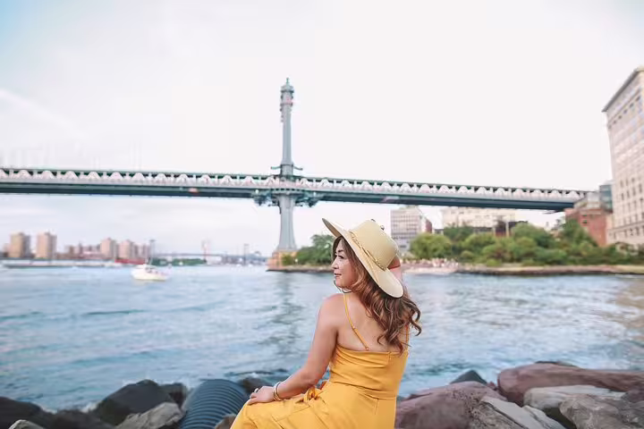 Woman in yellow dress by the East River with Manhattan Bridge views, Brooklyn and DUMBO photography tour NYC