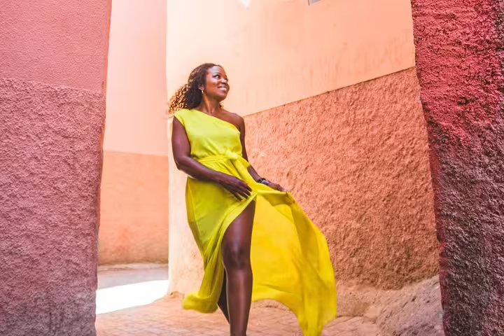 Woman in a vibrant yellow dress walking through the colorful streets of Marrakesh during a private photography session.