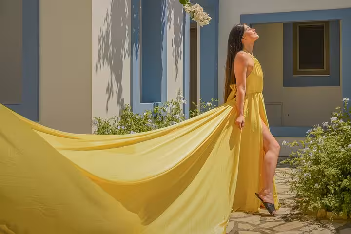 Woman in flowing yellow dress enjoys the sun during a Hersonissos flying dress photoshoot experience.