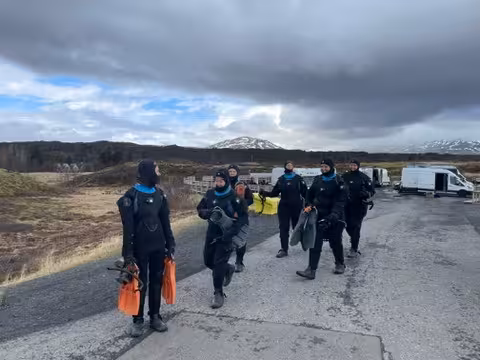 Group of women in wetsuits prepare for an adventurous cold-water dive in the scenic Icelandic landscape.