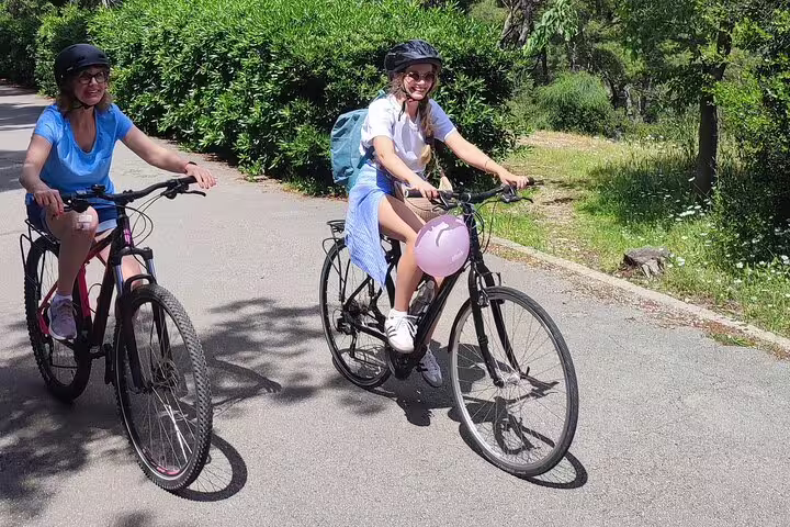 Two women cycling on a sunny path with helmets on, enjoying a guided Split City Bike Tour in Croatia