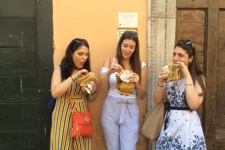 Three women enjoying local street food during the Vatican area walking food tour in Rome.